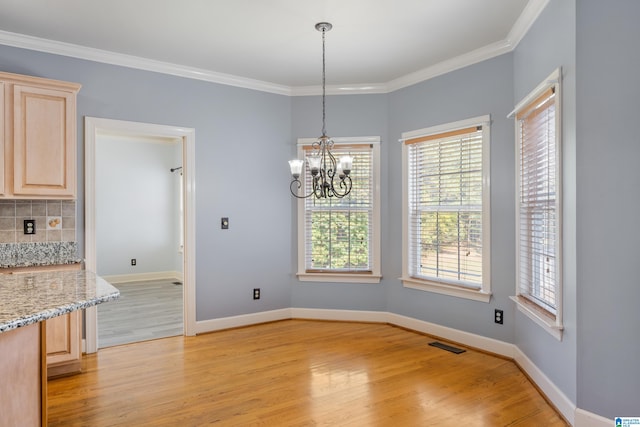 unfurnished dining area featuring crown molding, light hardwood / wood-style flooring, and a chandelier