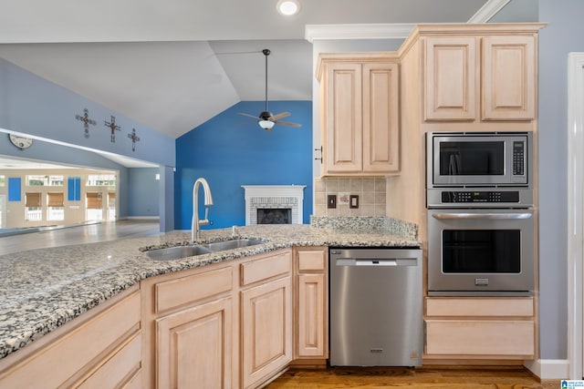 kitchen with vaulted ceiling, appliances with stainless steel finishes, sink, and light brown cabinets