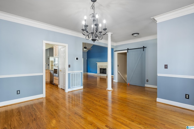 unfurnished dining area with ornamental molding, a brick fireplace, wood-type flooring, and an inviting chandelier