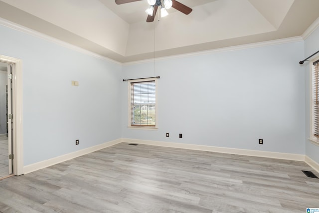 empty room featuring crown molding, a tray ceiling, light hardwood / wood-style floors, and ceiling fan