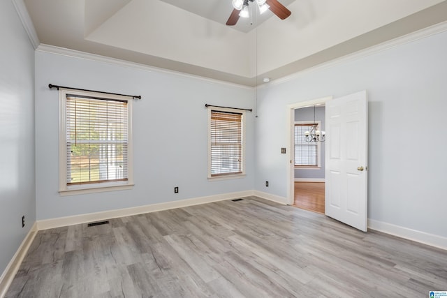 empty room with ornamental molding, light hardwood / wood-style flooring, and ceiling fan with notable chandelier