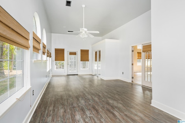 unfurnished living room featuring ceiling fan, dark hardwood / wood-style flooring, and a high ceiling