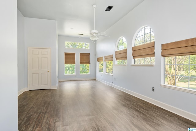 unfurnished room with dark wood-type flooring, ceiling fan, and a towering ceiling