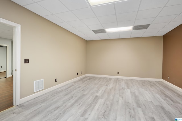 unfurnished room featuring light hardwood / wood-style flooring and a paneled ceiling