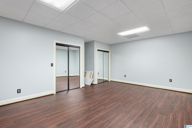 unfurnished bedroom featuring a drop ceiling and dark hardwood / wood-style floors