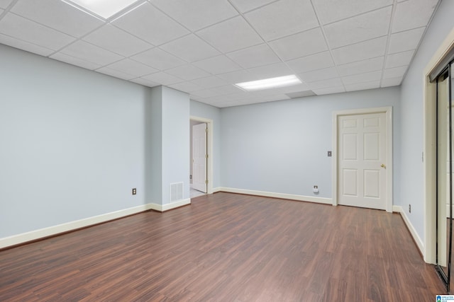 basement featuring a paneled ceiling and dark hardwood / wood-style flooring