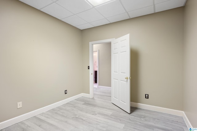 spare room with light hardwood / wood-style flooring and a paneled ceiling