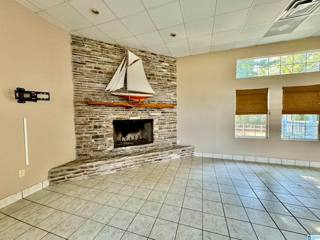 unfurnished living room with tile patterned flooring, a drop ceiling, plenty of natural light, and a fireplace