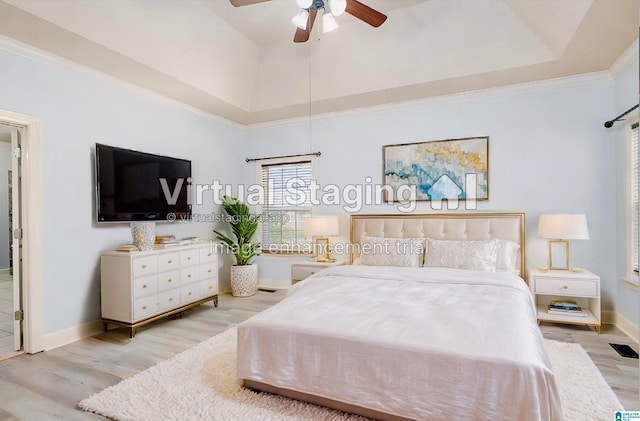 bedroom with crown molding, a raised ceiling, light hardwood / wood-style floors, and ceiling fan