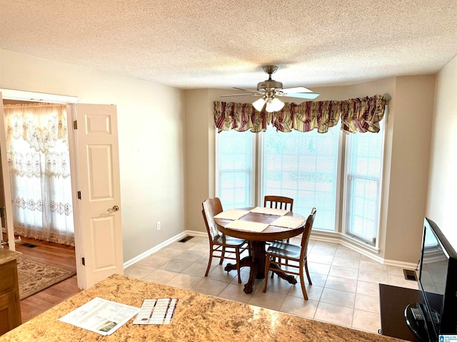 dining space featuring ceiling fan, a textured ceiling, light wood-type flooring, and a wealth of natural light