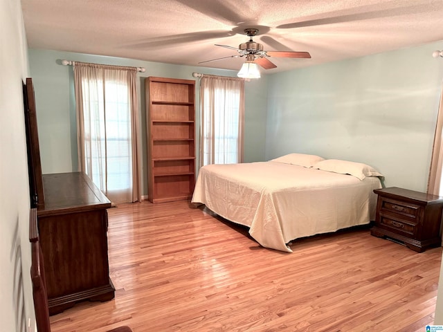 bedroom featuring light hardwood / wood-style floors, a textured ceiling, and ceiling fan