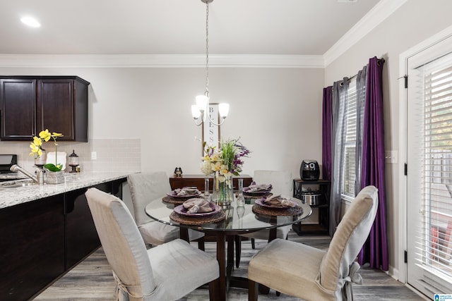 dining room with light hardwood / wood-style floors, crown molding, and an inviting chandelier