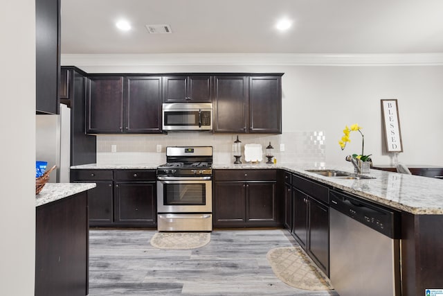 kitchen with sink, kitchen peninsula, light hardwood / wood-style floors, stainless steel appliances, and crown molding