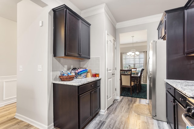 kitchen with tasteful backsplash, appliances with stainless steel finishes, light hardwood / wood-style floors, light stone counters, and ornamental molding