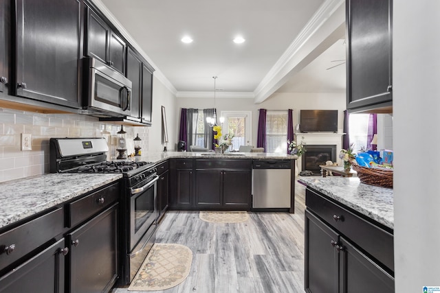 kitchen with ornamental molding, stainless steel appliances, sink, light hardwood / wood-style floors, and decorative light fixtures