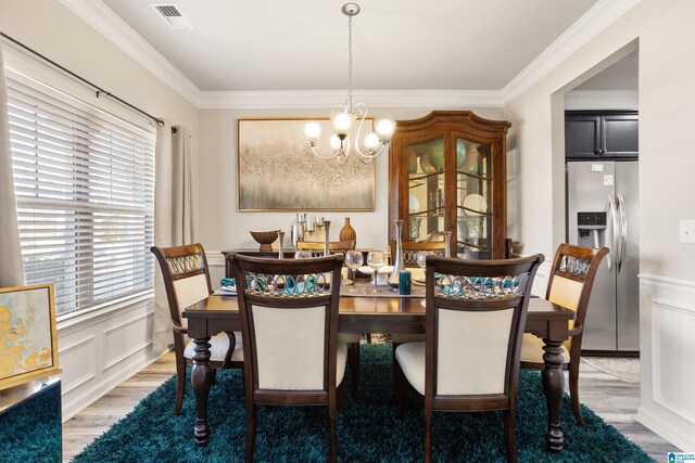 dining area featuring a notable chandelier, hardwood / wood-style flooring, and ornamental molding