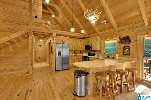 kitchen with light brown cabinets, beamed ceiling, appliances with stainless steel finishes, and light hardwood / wood-style flooring