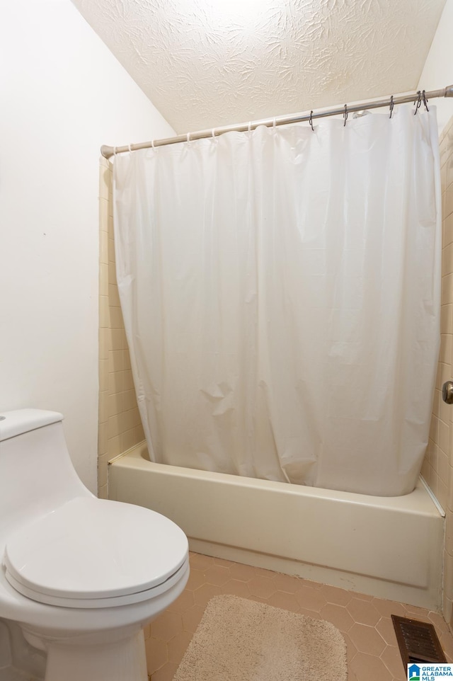 bathroom featuring a textured ceiling, tile patterned flooring, toilet, and shower / bath combo