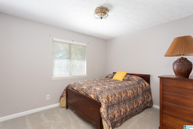 bedroom with light colored carpet and a textured ceiling