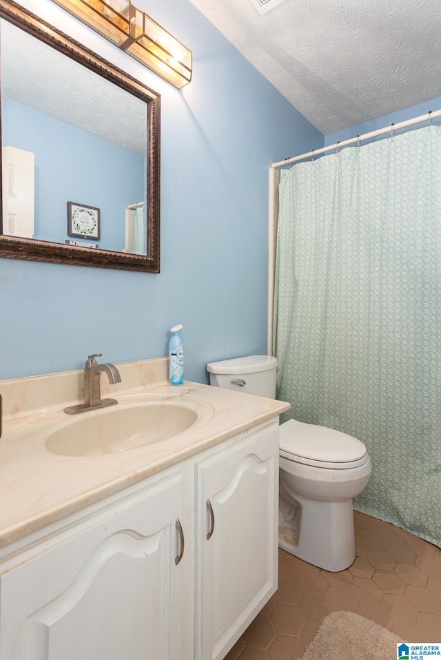 bathroom featuring toilet, a shower with curtain, tile patterned floors, vanity, and a textured ceiling