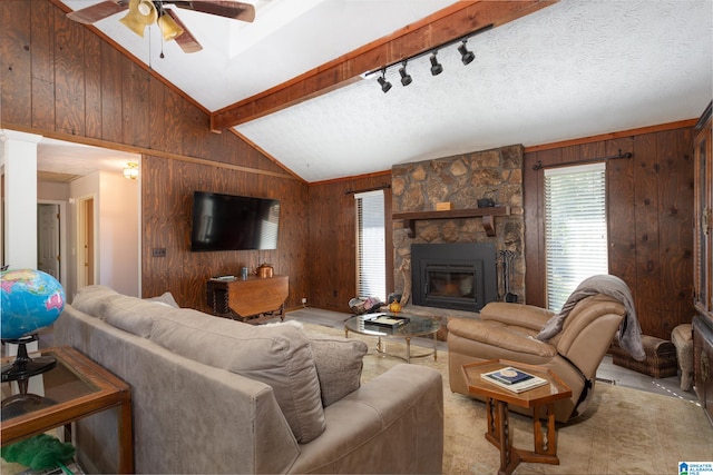 carpeted living room featuring a stone fireplace, a textured ceiling, wood walls, and beam ceiling