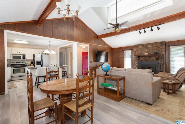 dining space with wood walls, light hardwood / wood-style floors, lofted ceiling with beams, and a fireplace