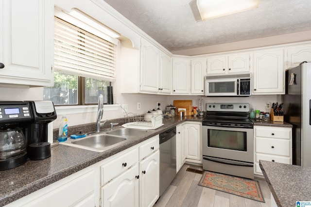 kitchen featuring white cabinets, appliances with stainless steel finishes, sink, and light wood-type flooring