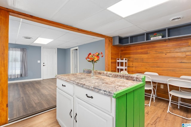 kitchen featuring light stone counters, light hardwood / wood-style flooring, a center island, and white cabinetry