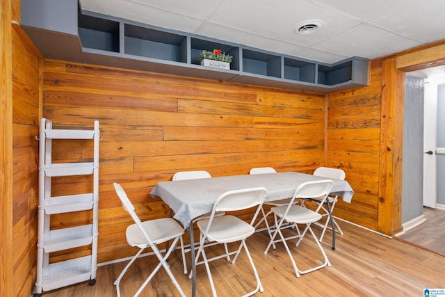 dining room with hardwood / wood-style floors and wooden walls