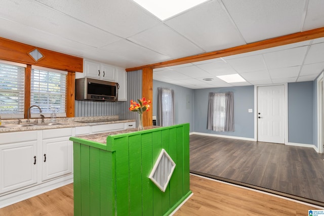 kitchen with a paneled ceiling, sink, light hardwood / wood-style flooring, and white cabinetry