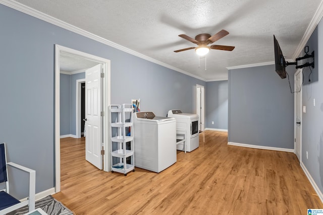 washroom with ornamental molding, washing machine and clothes dryer, and light hardwood / wood-style flooring