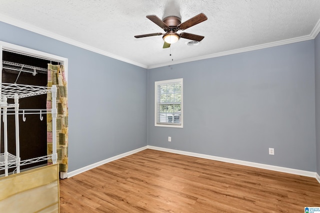 empty room featuring wood-type flooring, ceiling fan, ornamental molding, and a textured ceiling