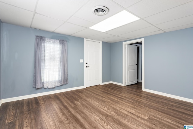 spare room with a drop ceiling and dark hardwood / wood-style flooring