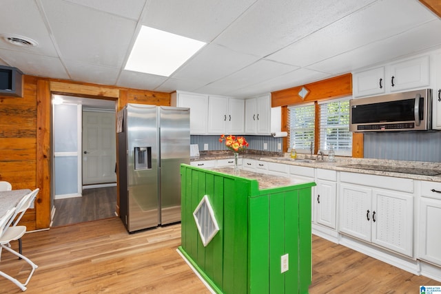 kitchen featuring white cabinets, stainless steel appliances, light wood-type flooring, and a kitchen island