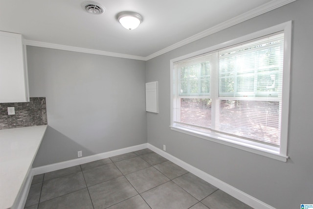 unfurnished dining area featuring tile patterned floors, plenty of natural light, and crown molding