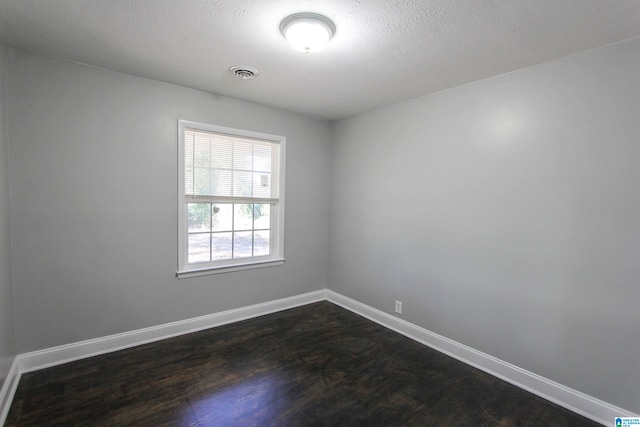 spare room with dark hardwood / wood-style flooring and a textured ceiling