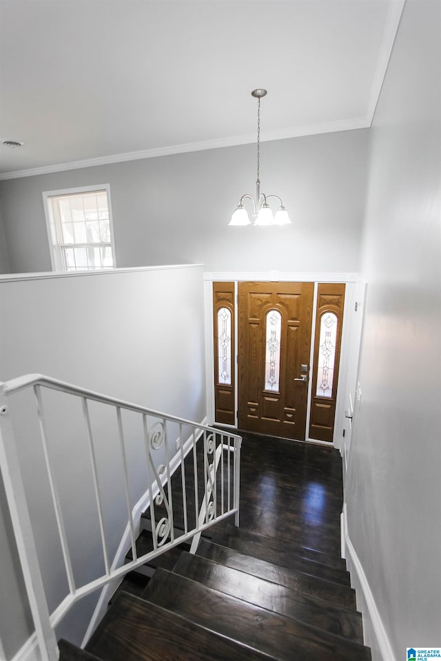 entryway featuring dark wood-type flooring, an inviting chandelier, and ornamental molding