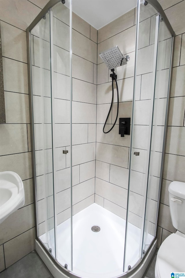 bathroom with toilet, an enclosed shower, and tile walls