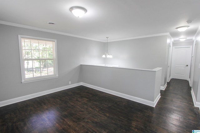 empty room with crown molding, dark hardwood / wood-style flooring, and an inviting chandelier