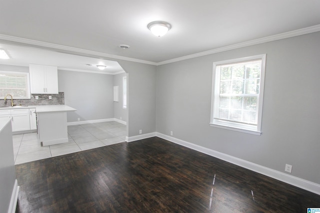 interior space with decorative backsplash, crown molding, sink, light hardwood / wood-style flooring, and white cabinets