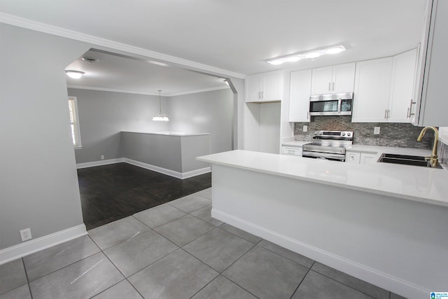 kitchen with pendant lighting, sink, appliances with stainless steel finishes, white cabinetry, and kitchen peninsula