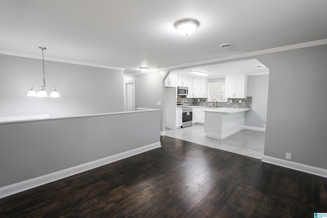 kitchen featuring kitchen peninsula, a chandelier, decorative light fixtures, white cabinets, and appliances with stainless steel finishes