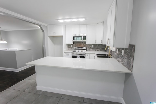 kitchen with sink, stainless steel appliances, dark tile patterned floors, pendant lighting, and white cabinets