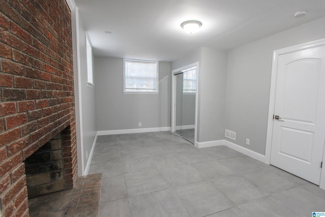 basement with brick wall and a brick fireplace