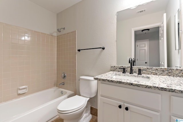 full bathroom featuring vanity, tiled shower / bath combo, and toilet