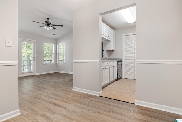 kitchen with ceiling fan, a skylight, beverage cooler, white cabinetry, and light wood-type flooring