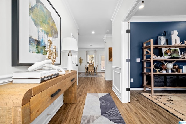 hallway featuring light hardwood / wood-style floors, ornamental molding, and a chandelier