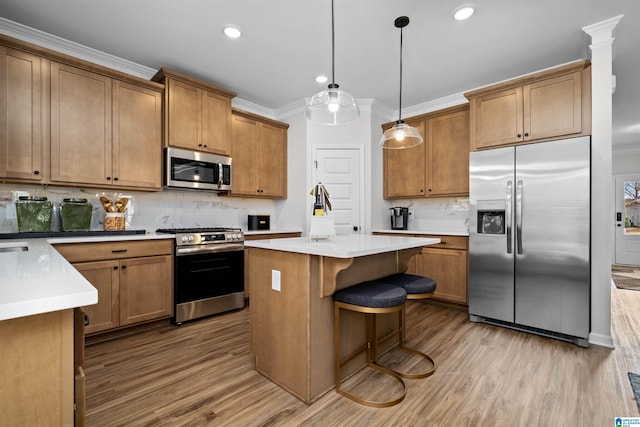 kitchen with decorative backsplash, light wood-type flooring, a kitchen island, pendant lighting, and stainless steel appliances