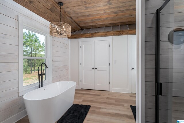 21023 Monroe Dunn Rd, Berry, AL 35546 - bathroom with wood-type flooring, wood ceiling, an inviting chandelier, wooden walls, and a tub to relax in