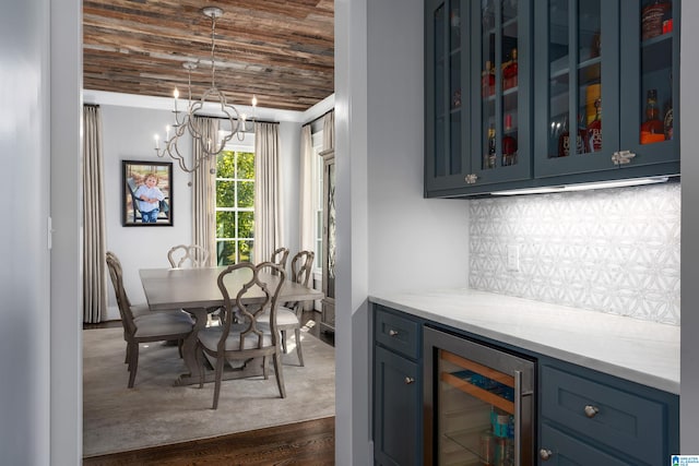 interior space with bar area, a notable chandelier, dark hardwood / wood-style flooring, wood ceiling, and beverage cooler